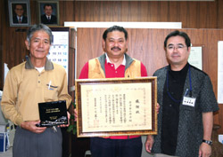 楚南会長（中央）と新垣自治会長（左）が受賞の喜びを報告